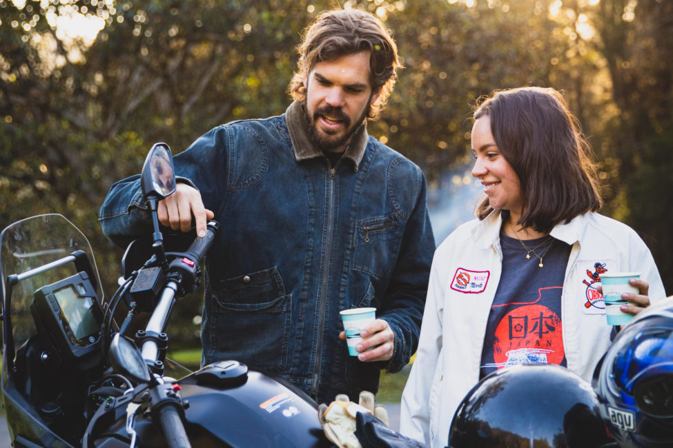 Couple drinking coffee beside a motorbike